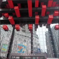 Interior reflections at Guotai Arts Center with glass walls framed by red and black beams