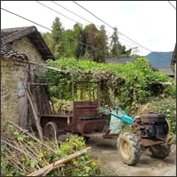 Small tractor parked outside stone village homes.