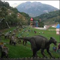 Dinosaur sculptures displayed in a landscaped outdoor attraction area.